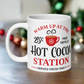 This ceramic glossy coffee mug says Warm Up At The Hot Cocoa Station Served Fresh Daily.It features a cute little red cup with a snowflake on it.