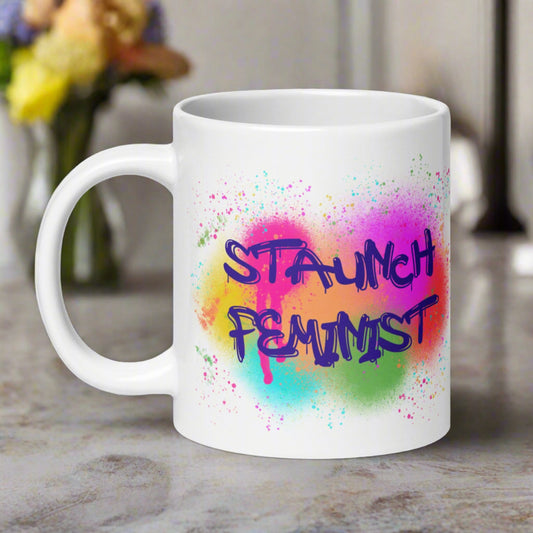 This ceramic glossy coffee mug features original artwork of spray painted Staunch Feminist with colorful sprays behind the lettering.