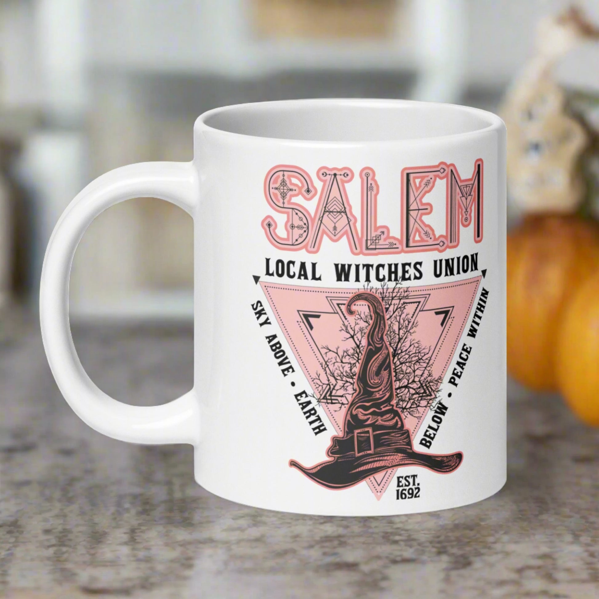 This ceramic glossy mug says Salem Local Witches Union and features a pointy pink and black witch's hat. It says Sky Above Earth Below Peace Within Est 1692.