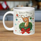 This ceramic glossy coffee mug is a midcentury christmas illustration that says Wishing you Christmas Joy. It features a reindeer with her tongue out wearing a Christmas wreath with a red bow. Her antlers are decorated with tinsel and  ornaments.