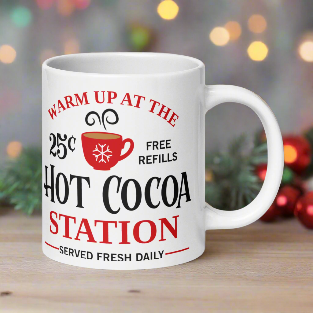 This ceramic glossy coffee mug says Warm Up At The Hot Cocoa Station Served Fresh Daily.It features a cute little red cup with a snowflake on it.