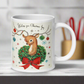 This ceramic glossy coffee mug is a midcentury christmas illustration that says Wishing you Christmas Joy. It features a reindeer with her tongue out wearing a Christmas wreath with a red bow. Her antlers are decorated with tinsel and  ornaments.